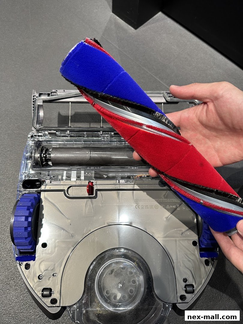 A hand holds a dual-material brush bar for a Dyson vacuum cleaner.