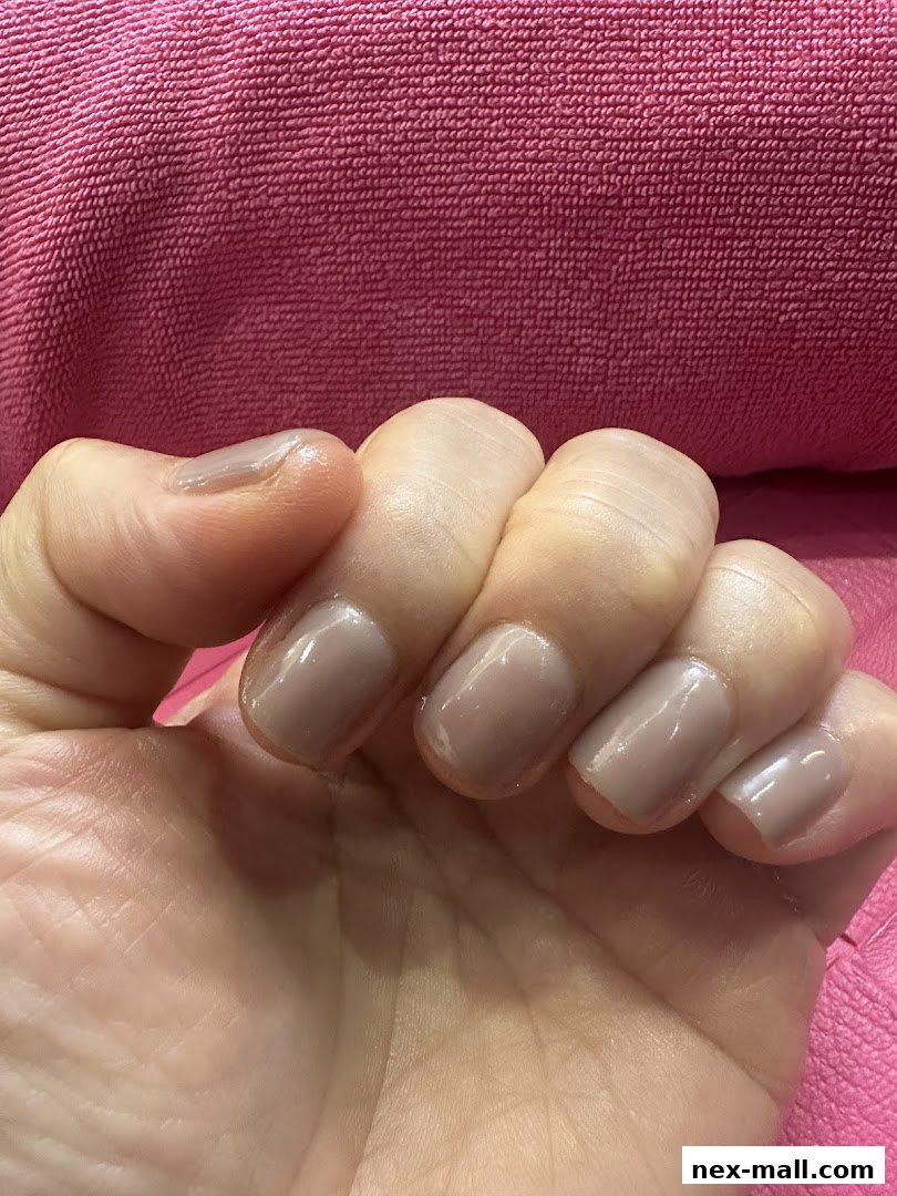 A close-up of a hand with neatly manicured nails in a neutral shade.
