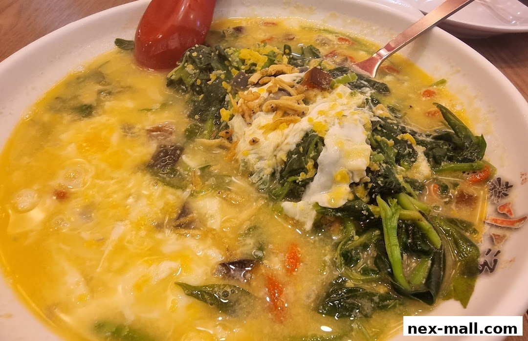 A close-up of a steaming bowl of soup with vegetables and egg.