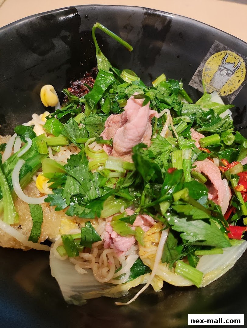 A close-up of a bowl of Mala Tang with noodles, meat, vegetables, and chili.