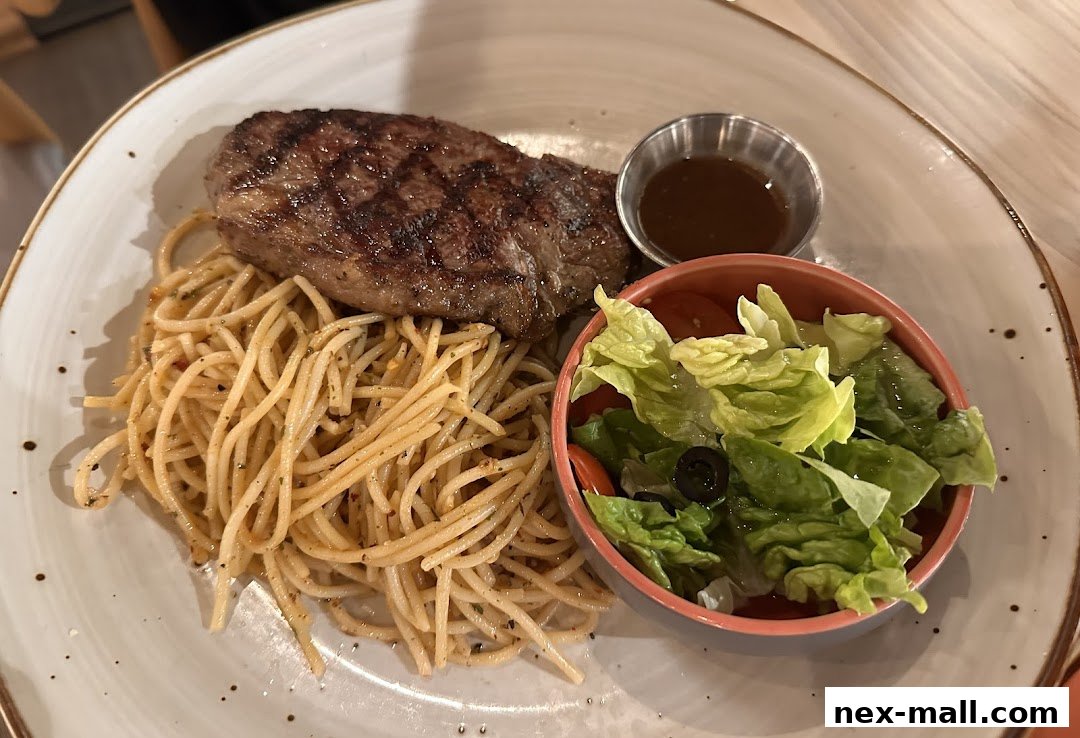 A grilled steak served with spaghetti and a side salad.