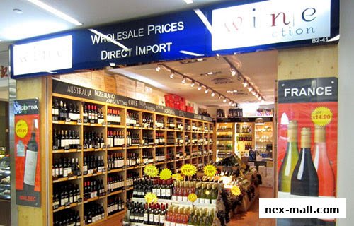 Interior view of a wine shop with shelves stocked with bottles and promotional displays.