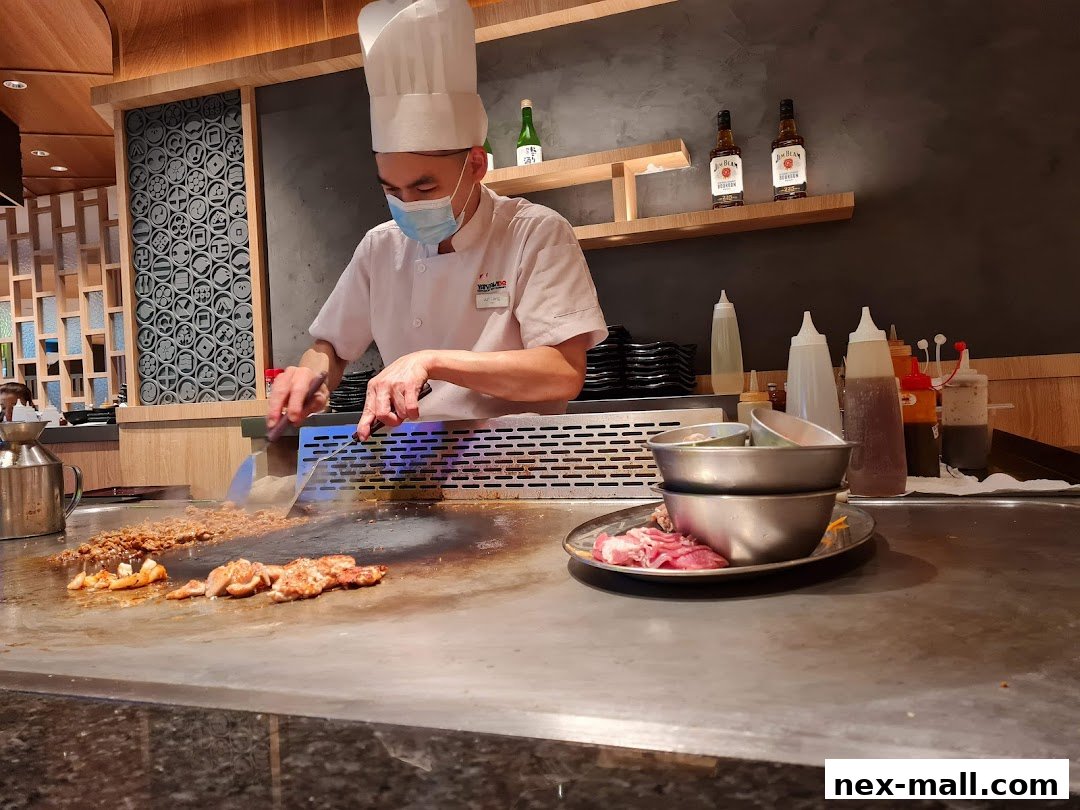 A chef in uniform cooks food on a teppanyaki grill with various ingredients and sauces.