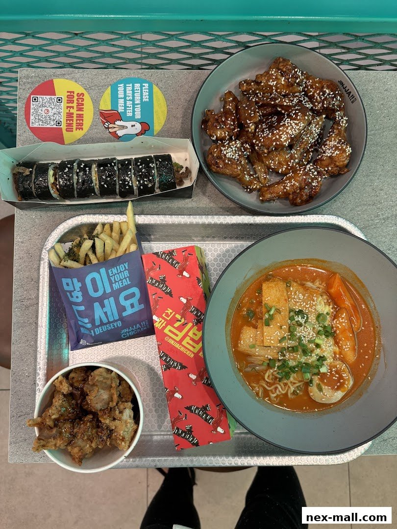 A tray of Korean food including fried chicken, kimbap, fries, and tteokbokki.