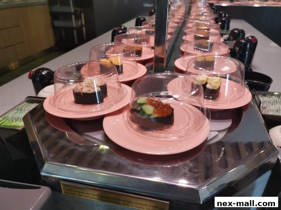 Conveyor belt sushi with various types of sushi displayed on pink plates.