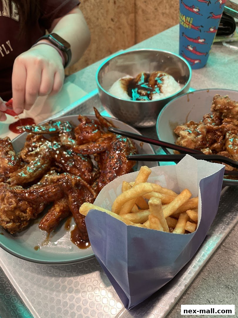 A close-up of delicious Korean fried chicken wings and fries served at JINJJA Chicken.