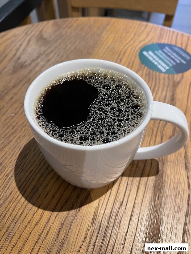 A white mug filled with dark coffee sits on a wooden table.