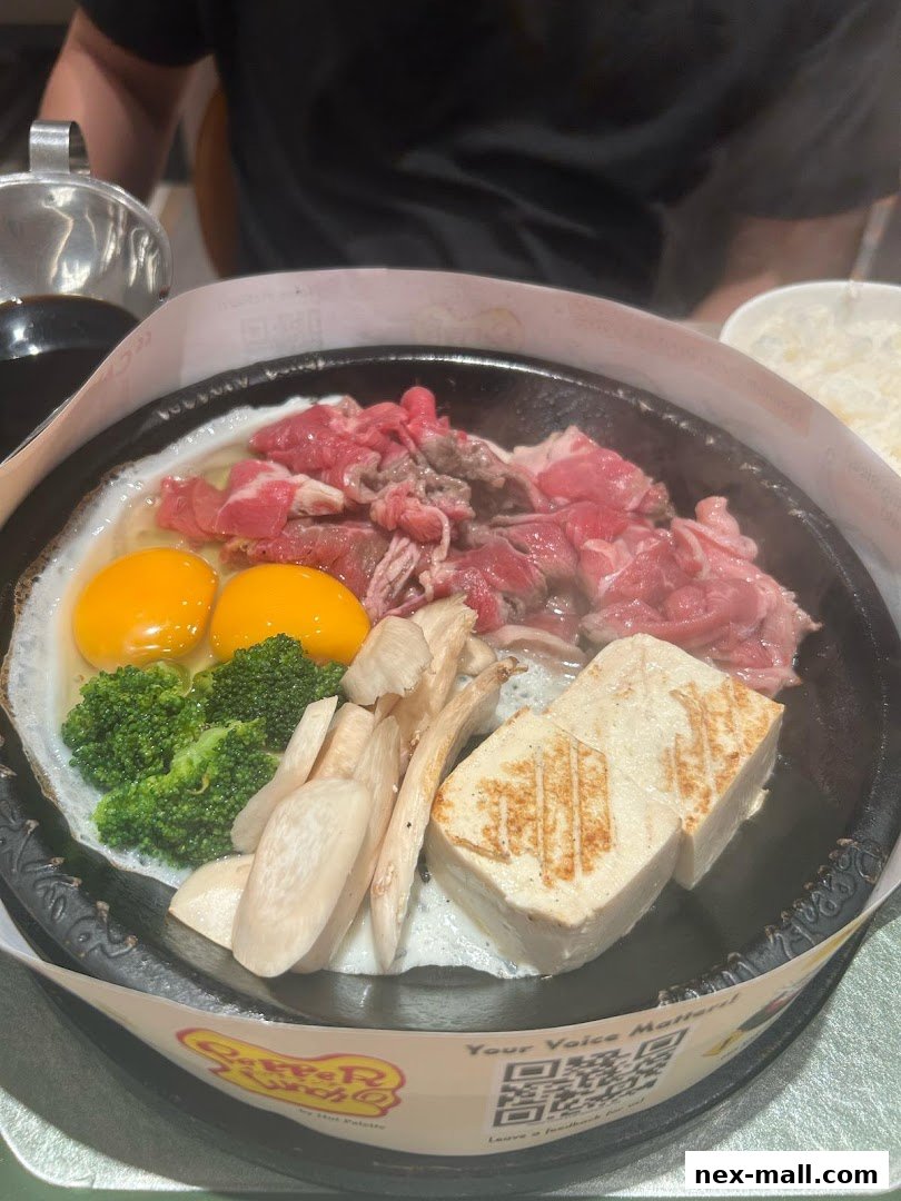 A sizzling hot plate dish with beef, eggs, broccoli, mushrooms, and tofu.