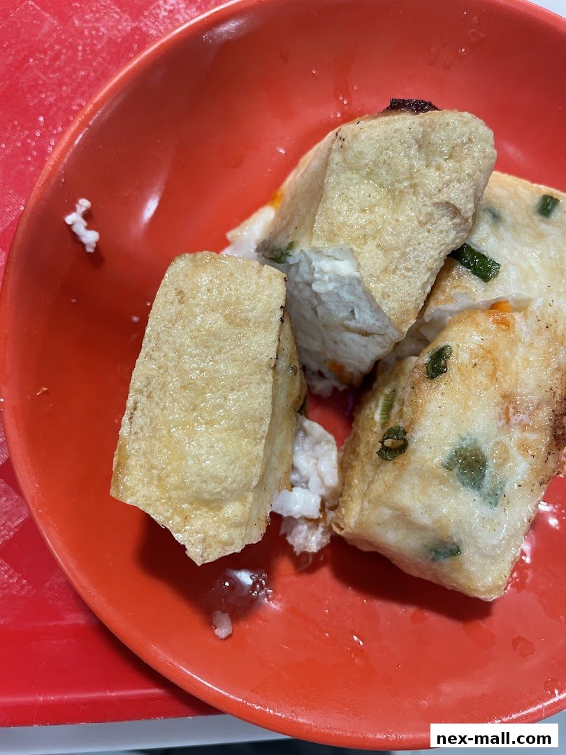 Close-up of fried tofu stuffed with fish paste and spring onions in a red bowl.