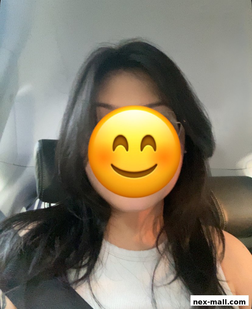A person with long dark hair and a smiley face emoji covering their face.