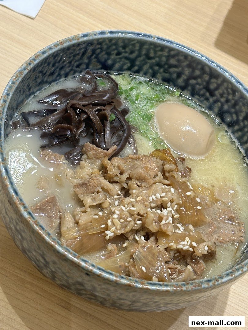 A close-up of a steaming bowl of ramen with beef, egg, and wood ear mushrooms.