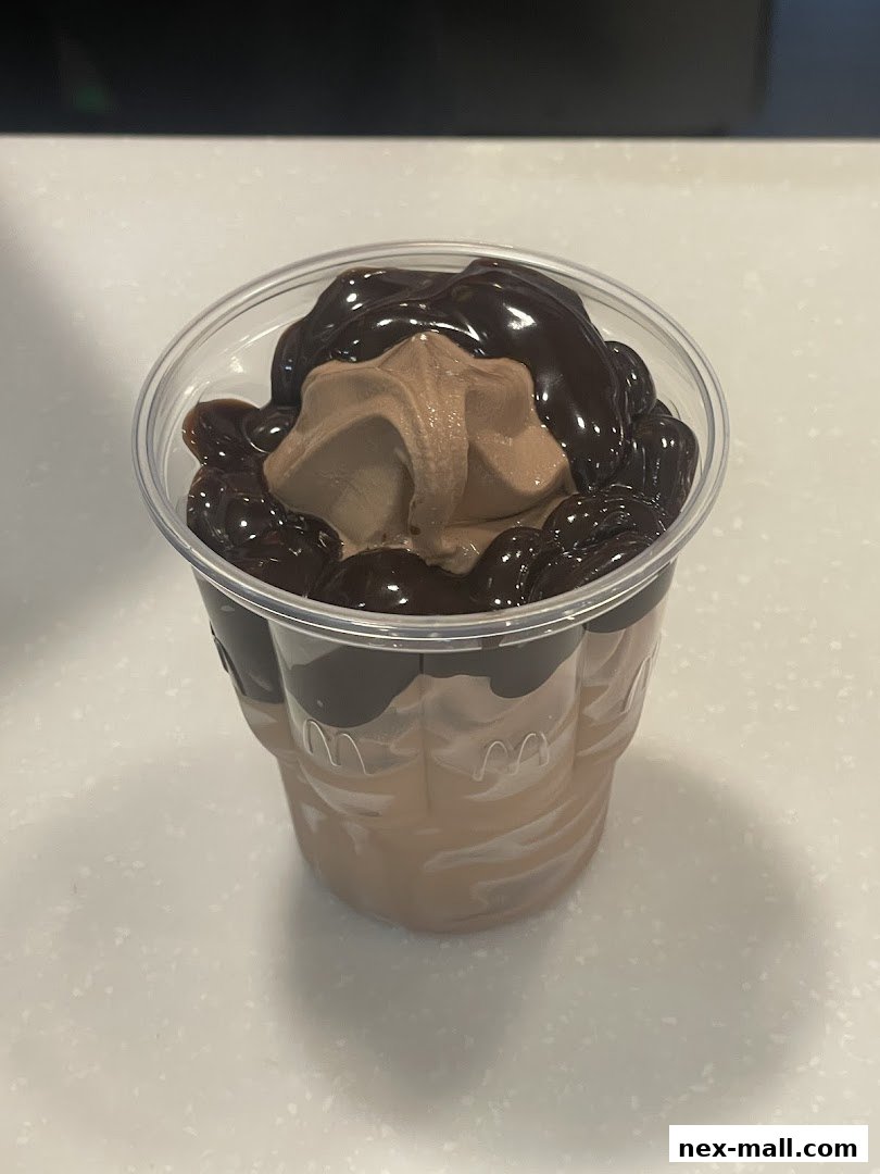 A close-up of a chocolate sundae with hot fudge and whipped cream in a clear cup.