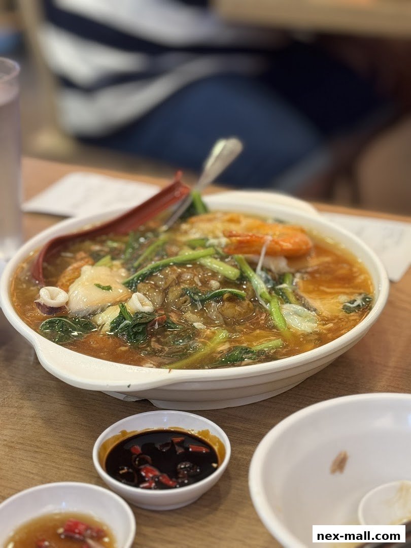 A close-up of a hearty bowl of noodle soup with seafood and vegetables.