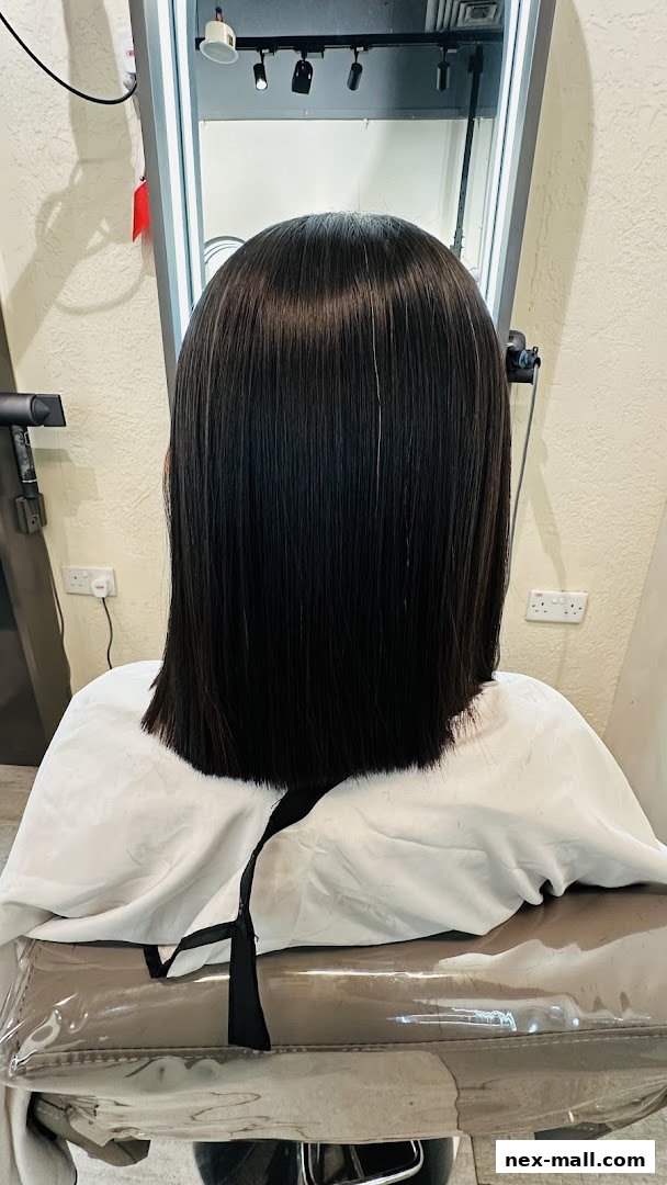 Back view of a person with freshly cut, sleek, dark hair in a salon.