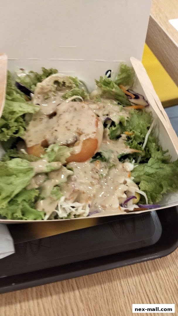 A fresh salad with lettuce, tomato, and dressing in a white takeout box.