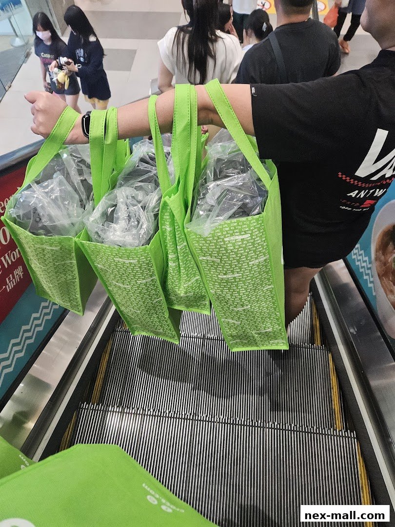 A person carrying multiple bright green shopping bags with text on an escalator.