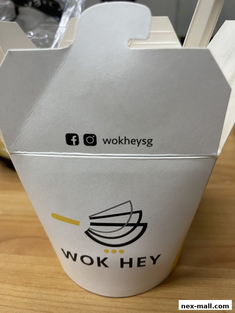 A close-up of a Wok Hey takeaway container with social media handles.