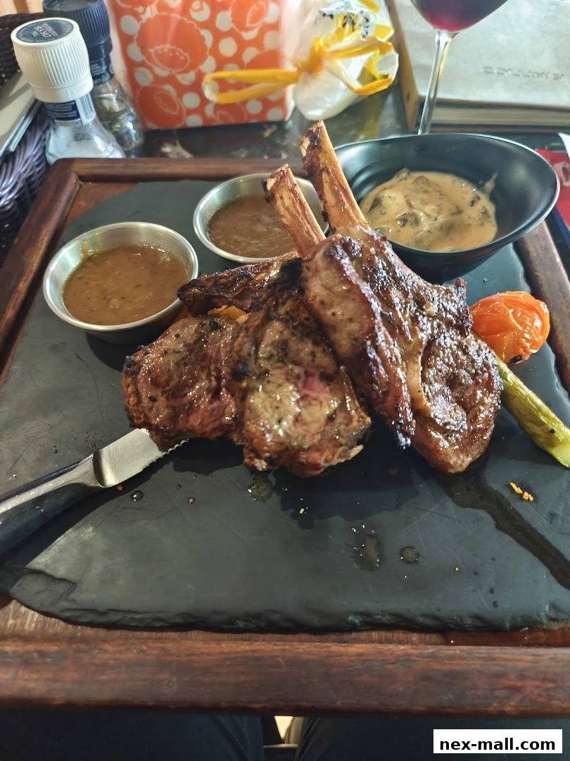 A plate of grilled lamb chops with dipping sauces and a side of asparagus.