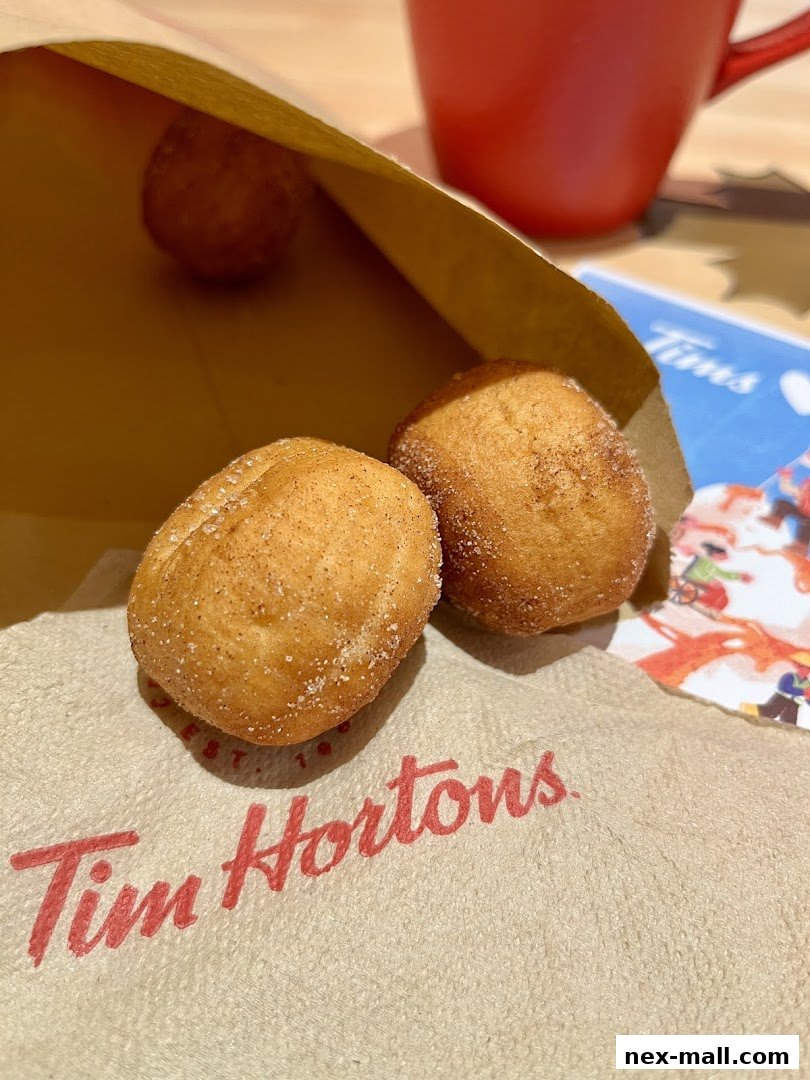 Tim Hortons donut holes in a paper bag with a red mug in the background.