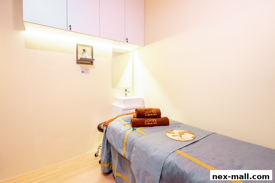 A clean and serene spa room with a massage bed, towels, and a sink.