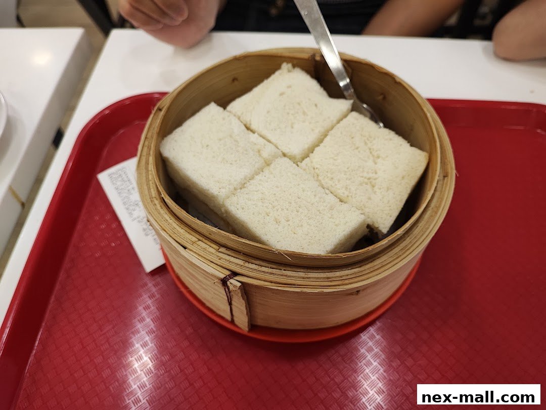 A close-up of steamed bread slices in a bamboo steamer on a red tray.