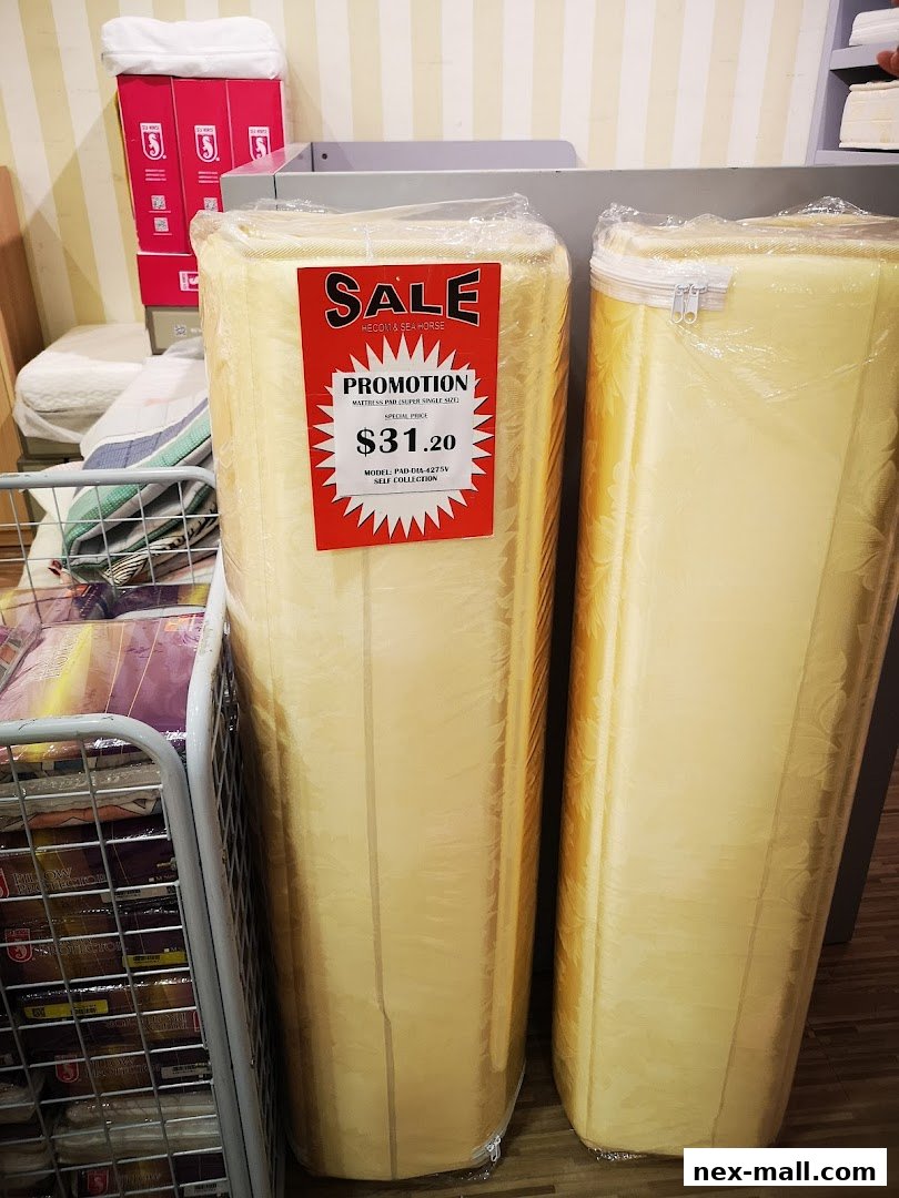 Rolled up mattress pads are displayed with a sale promotion tag.