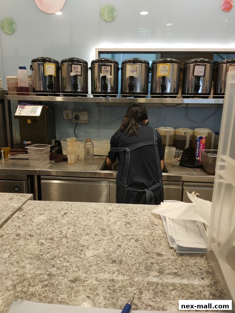 A staff member works behind the counter at PlayMade, with large beverage dispensers visible.