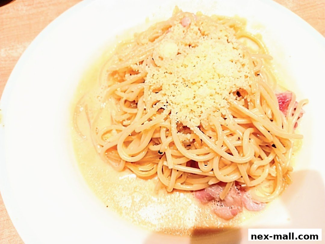 A close-up shot of a creamy spaghetti carbonara dish topped with grated cheese.