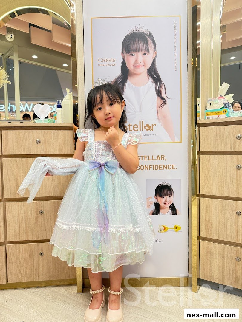 A young girl in a sparkly dress poses in front of a Stellar NEX poster.