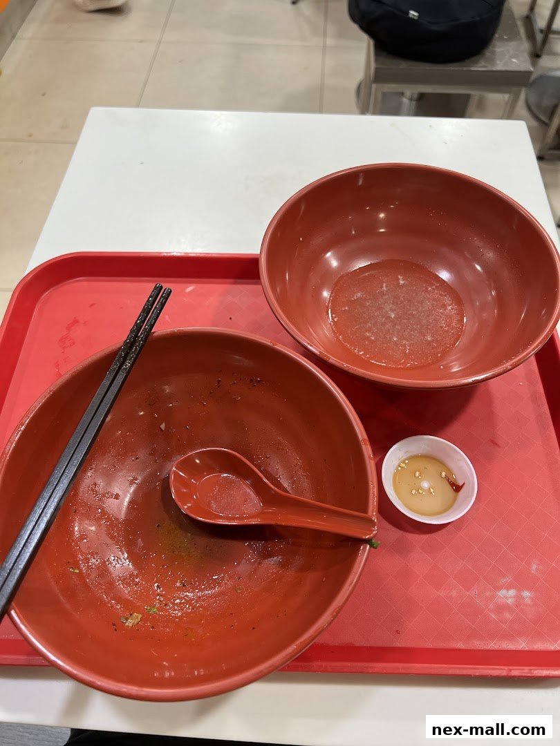 Two empty red bowls with chopsticks and a small dipping sauce dish on a red tray.