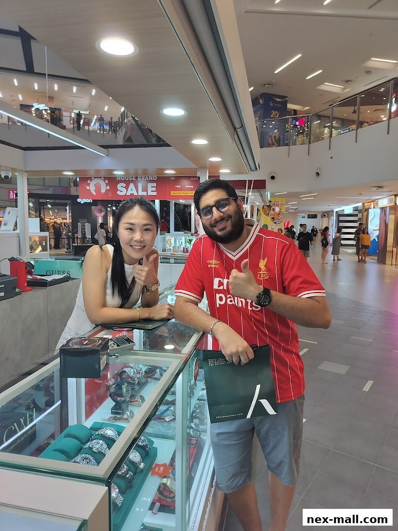 A smiling woman and man give thumbs up at a watch store counter.