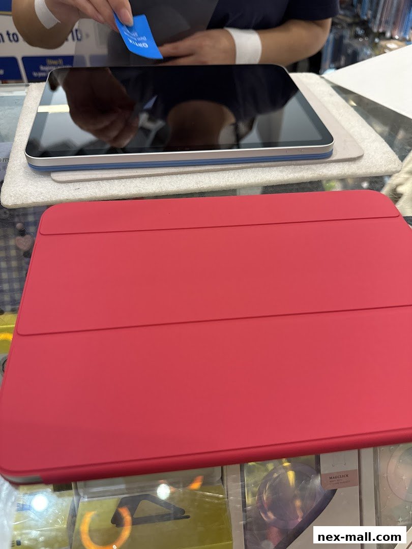 A person is applying a screen protector to a tablet, with a red tablet case in the foreground.