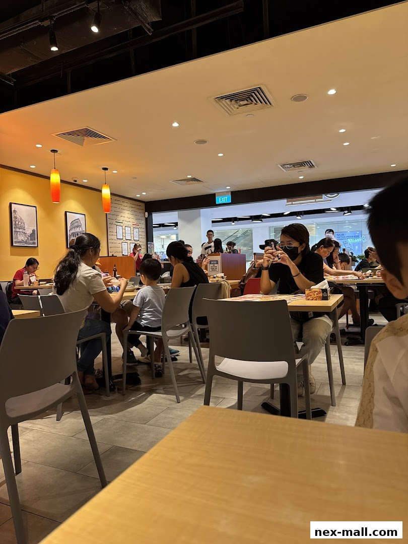 Diners are seated at tables inside a brightly lit restaurant, with some people looking at their phones.