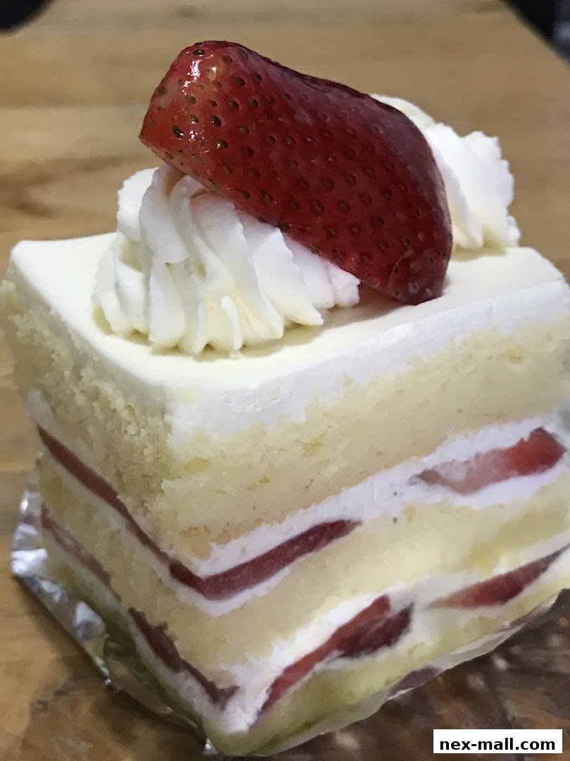 A slice of strawberry shortcake with fresh cream and a strawberry on top.