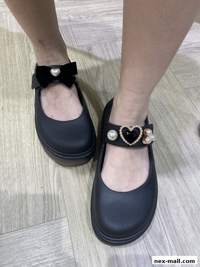 A pair of black Crocs shoes with decorative bows and pearl embellishments on the straps.