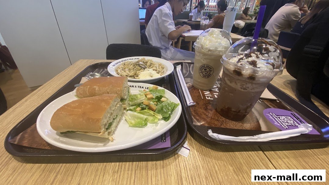A tray with a sandwich, salad, pasta, and two iced beverages from The Coffee Bean & Tea Leaf.
