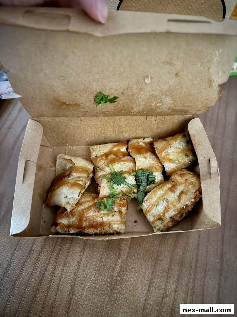 A box of fried Taiwanese snacks, likely oyster omelets, drizzled with sauce and garnished with cilantro.