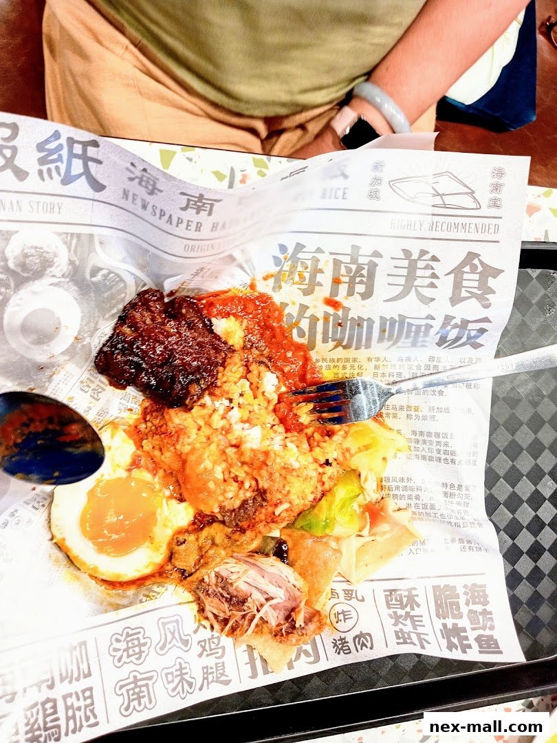 A plate of Hainanese food served on newspaper with a person's lap visible.