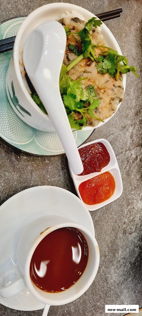 A close-up of a bowl of food with rice, meat, and cilantro, served with dipping sauces and a cup of coffee.