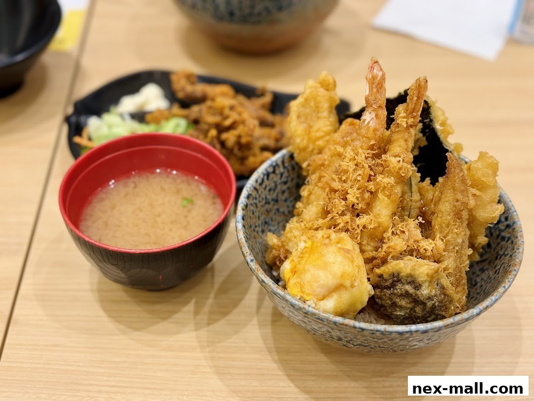 A close-up of a Japanese tempura rice bowl with miso soup and fried items.