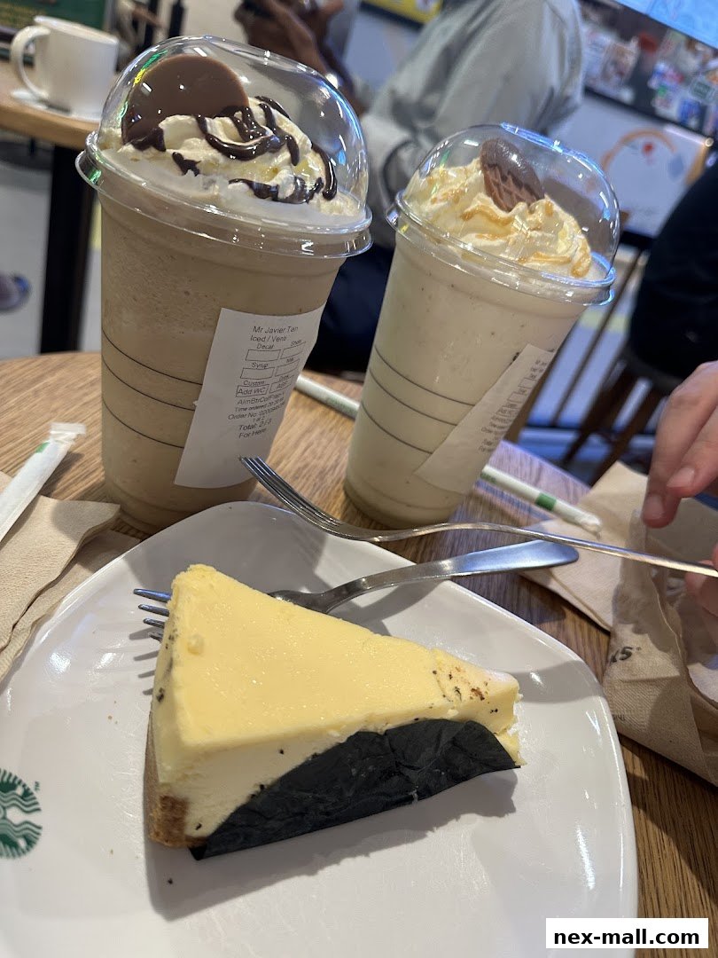 A slice of cheesecake and two iced beverages with whipped cream and toppings.