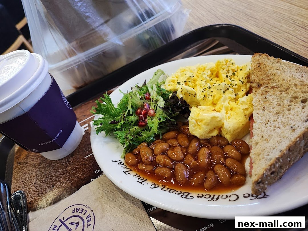 A breakfast plate with scrambled eggs, baked beans, salad, and toast, alongside a coffee cup.