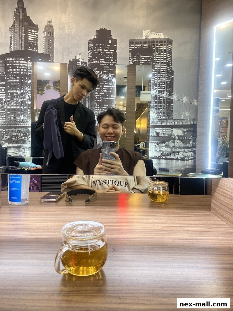 A hairstylist gives a thumbs-up to a client taking a selfie in a salon.