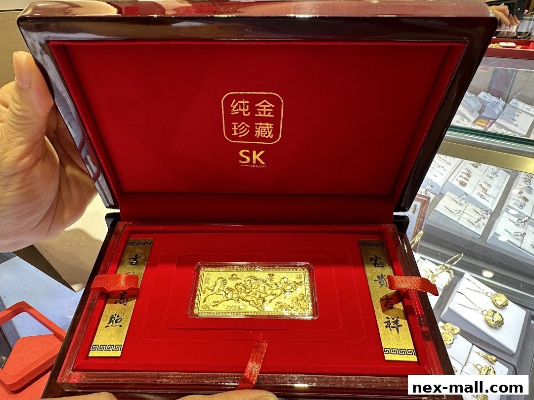 A hand holds open a luxurious red box revealing a gold bar with intricate designs and Chinese calligraphy.