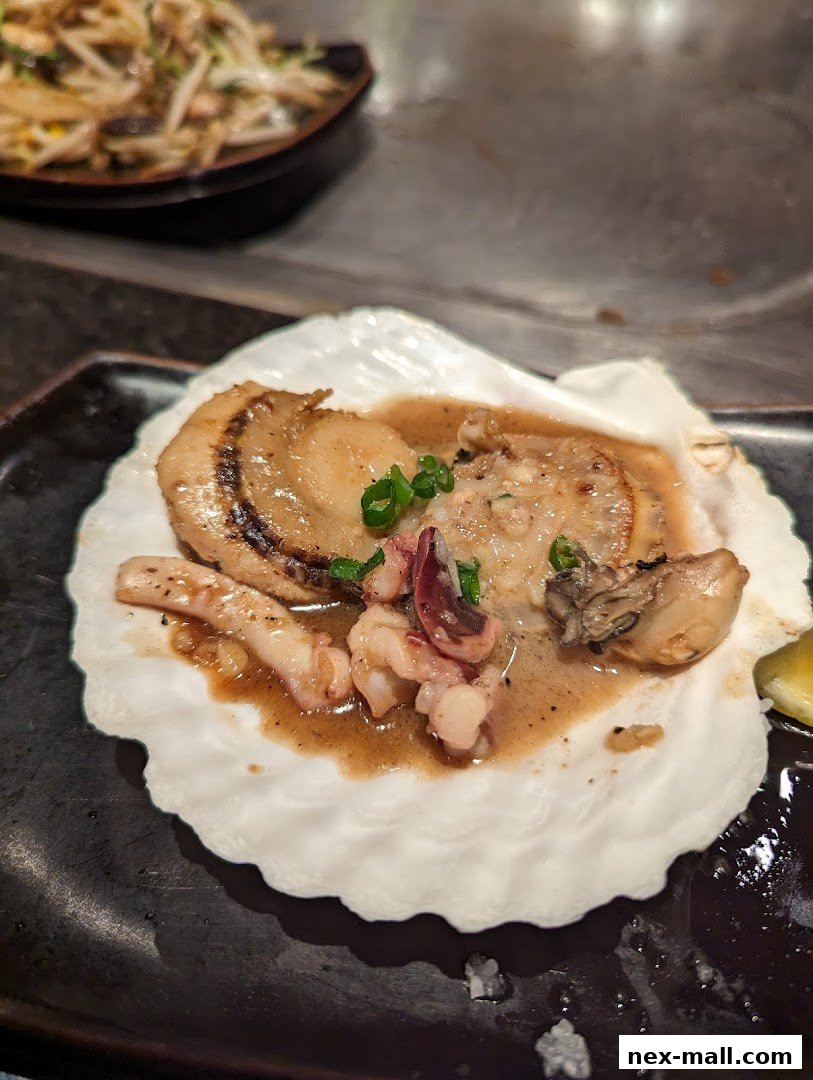 A close-up of a scallop dish served in a shell with other seafood and sauce.