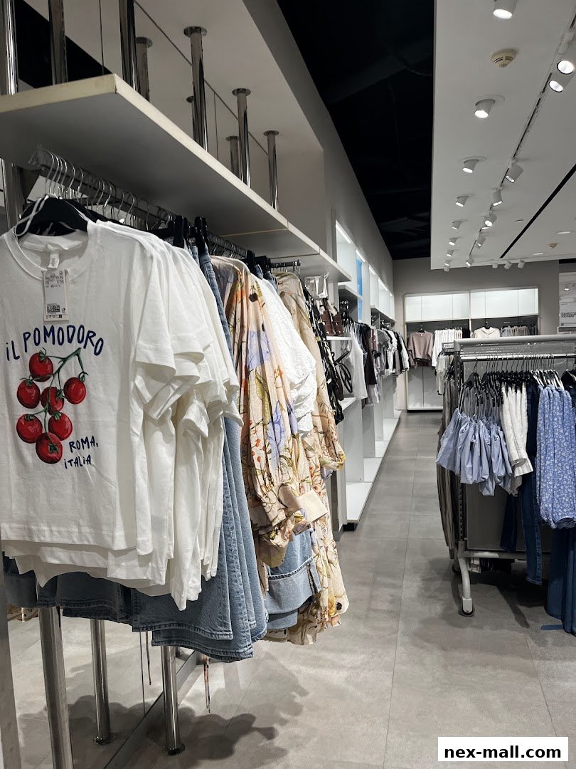 Interior view of a clothing store with racks of apparel, including t-shirts and dresses.