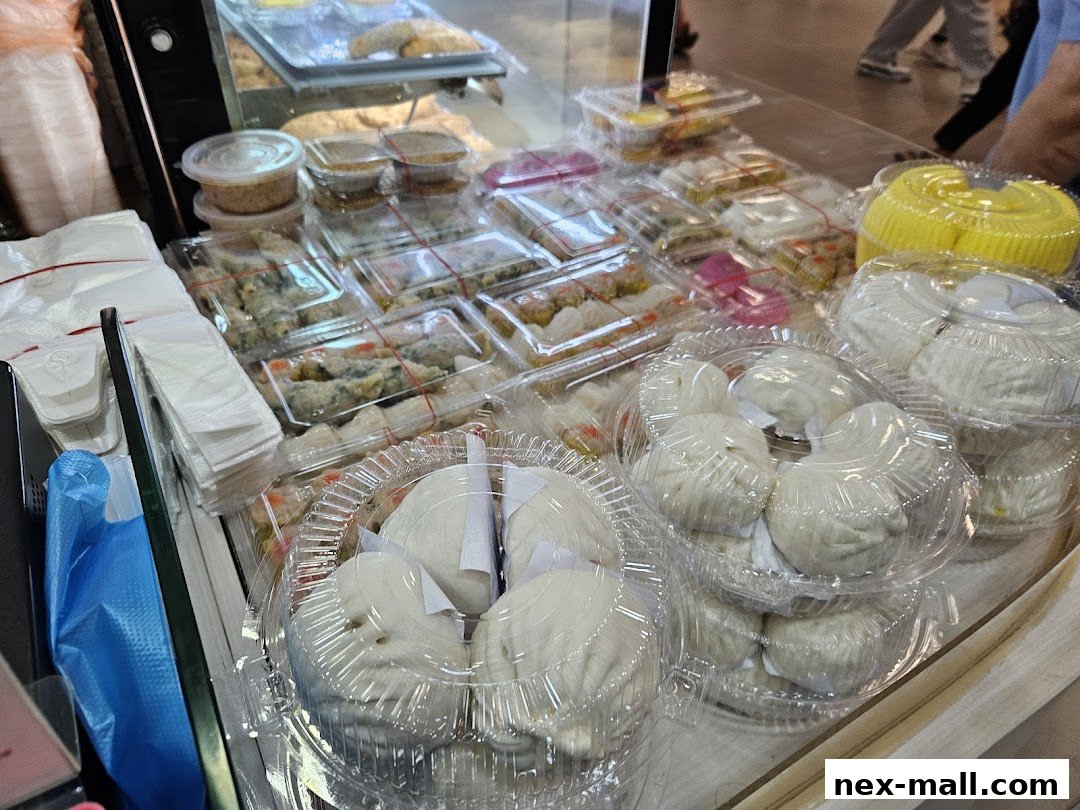 A display of freshly steamed buns and other dim sum items in clear plastic containers.