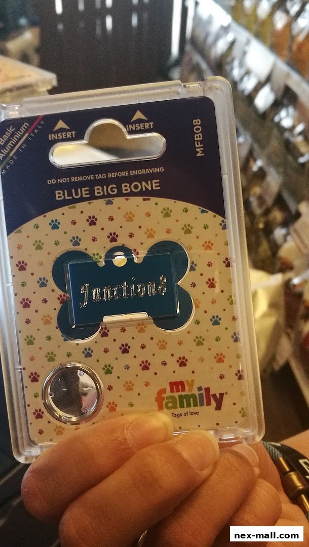 A person holds a packaged blue bone-shaped pet tag with the name 'Junctions' engraved.