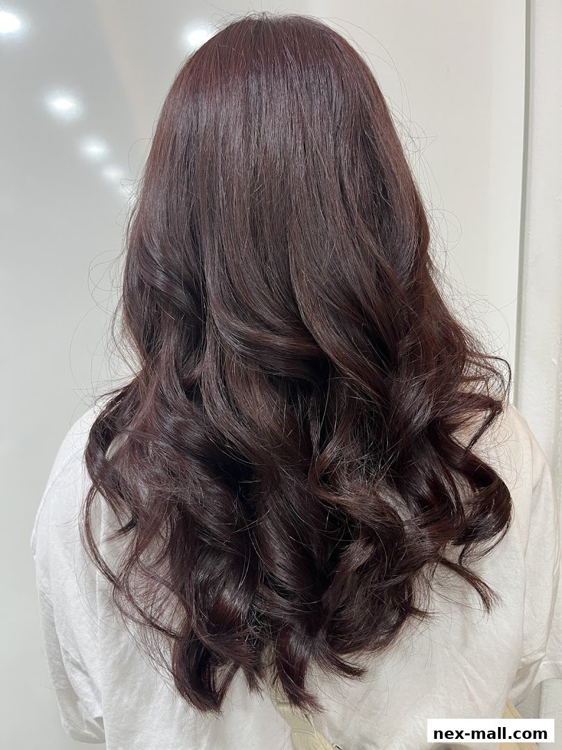 A person's back with long, dark, wavy hair styled with volume.