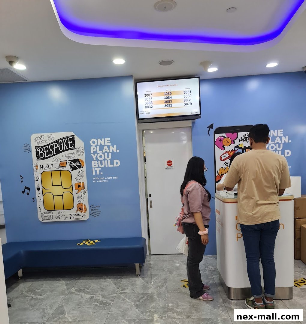 Customers wait at a counter in a brightly lit phone shop with a digital display showing queue numbers.